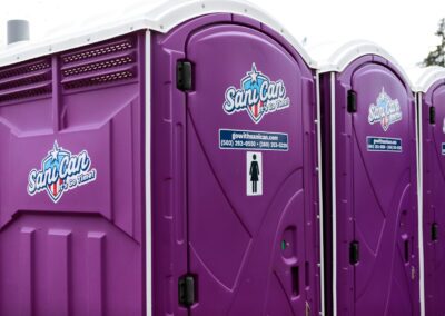Close-up of clean, purple portable restrooms featuring white roofing and high-visibility branding for public gatherings.